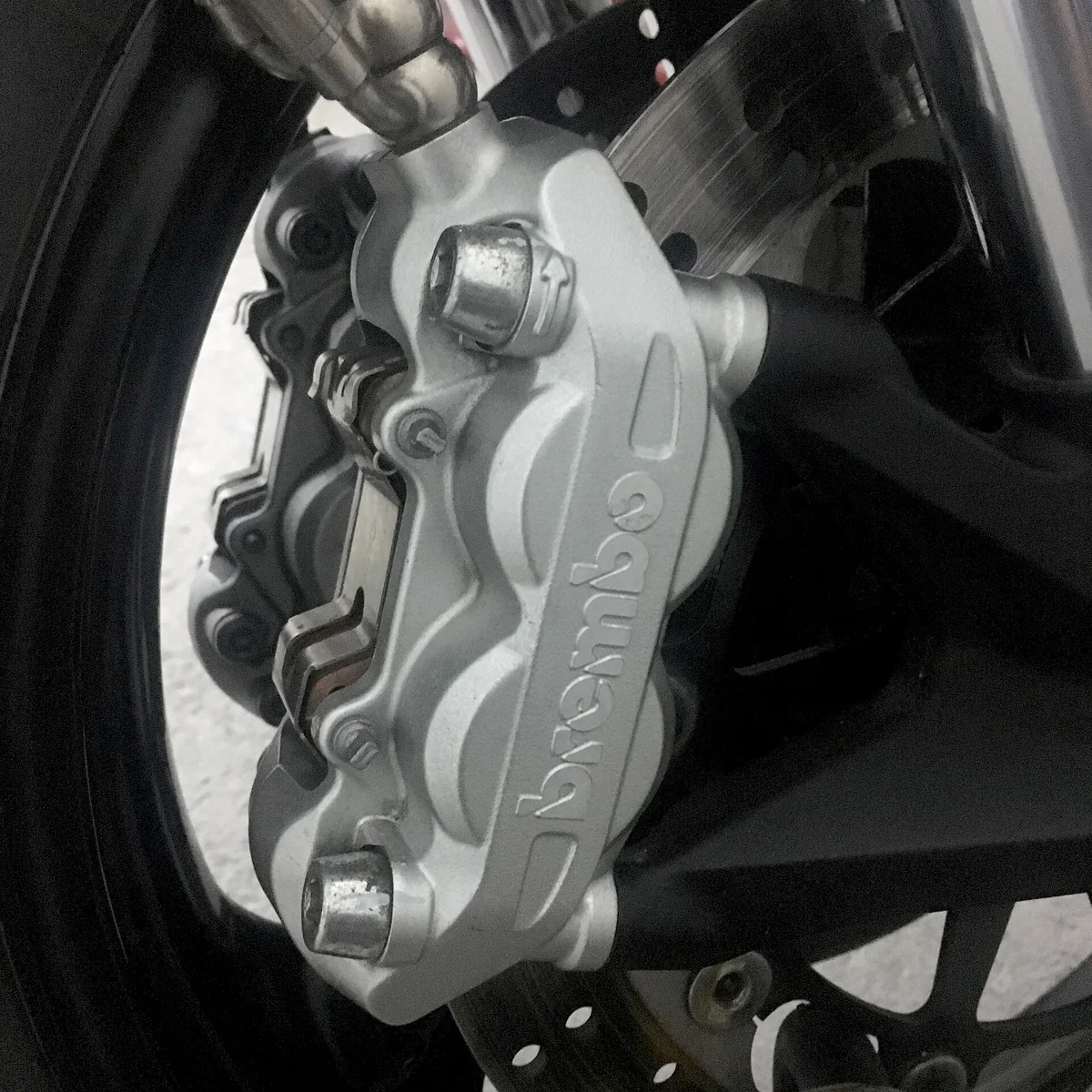 close-up of a Brembo four-piston fixed brake caliper mounted beside a brake disc