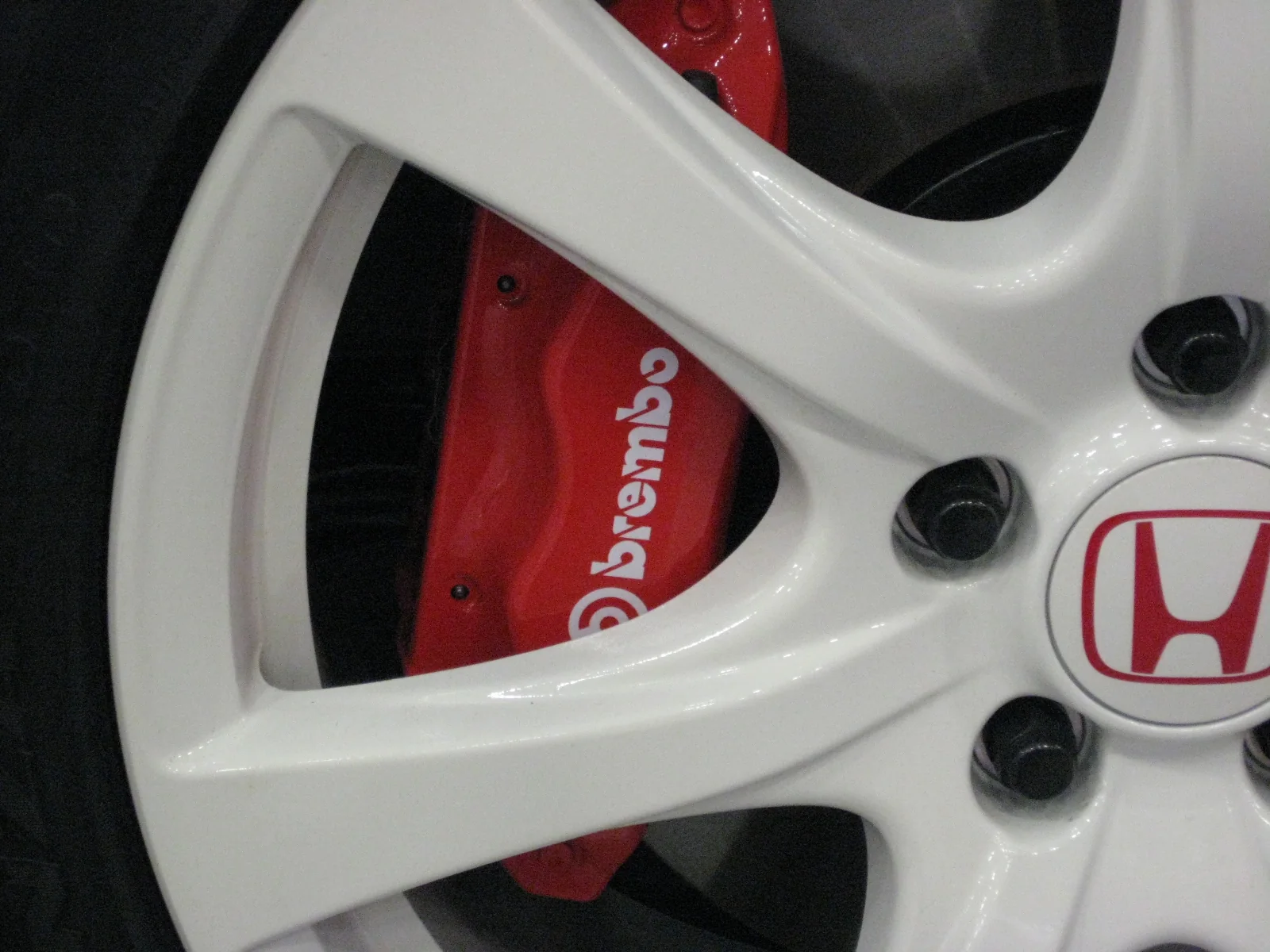red Brembo brake caliper visible through a white alloy wheel on a performance car