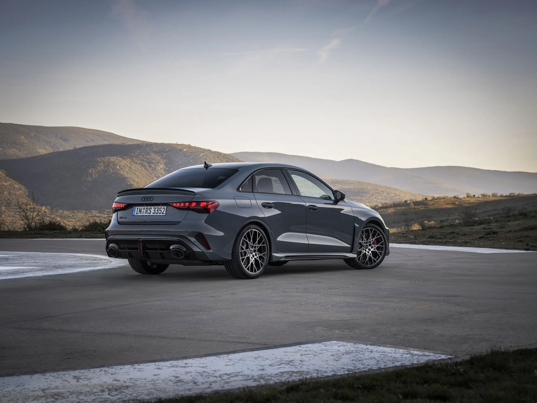 Grey Audi RS 3 Sedan viewed from the rear quarter beside a mountain road