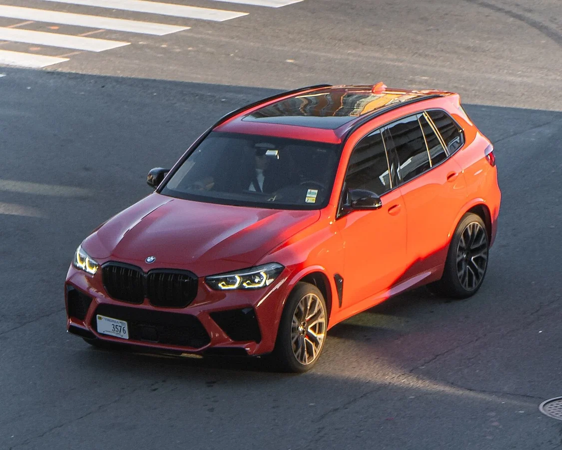 Orange BMW X5 M F95 in street traffic