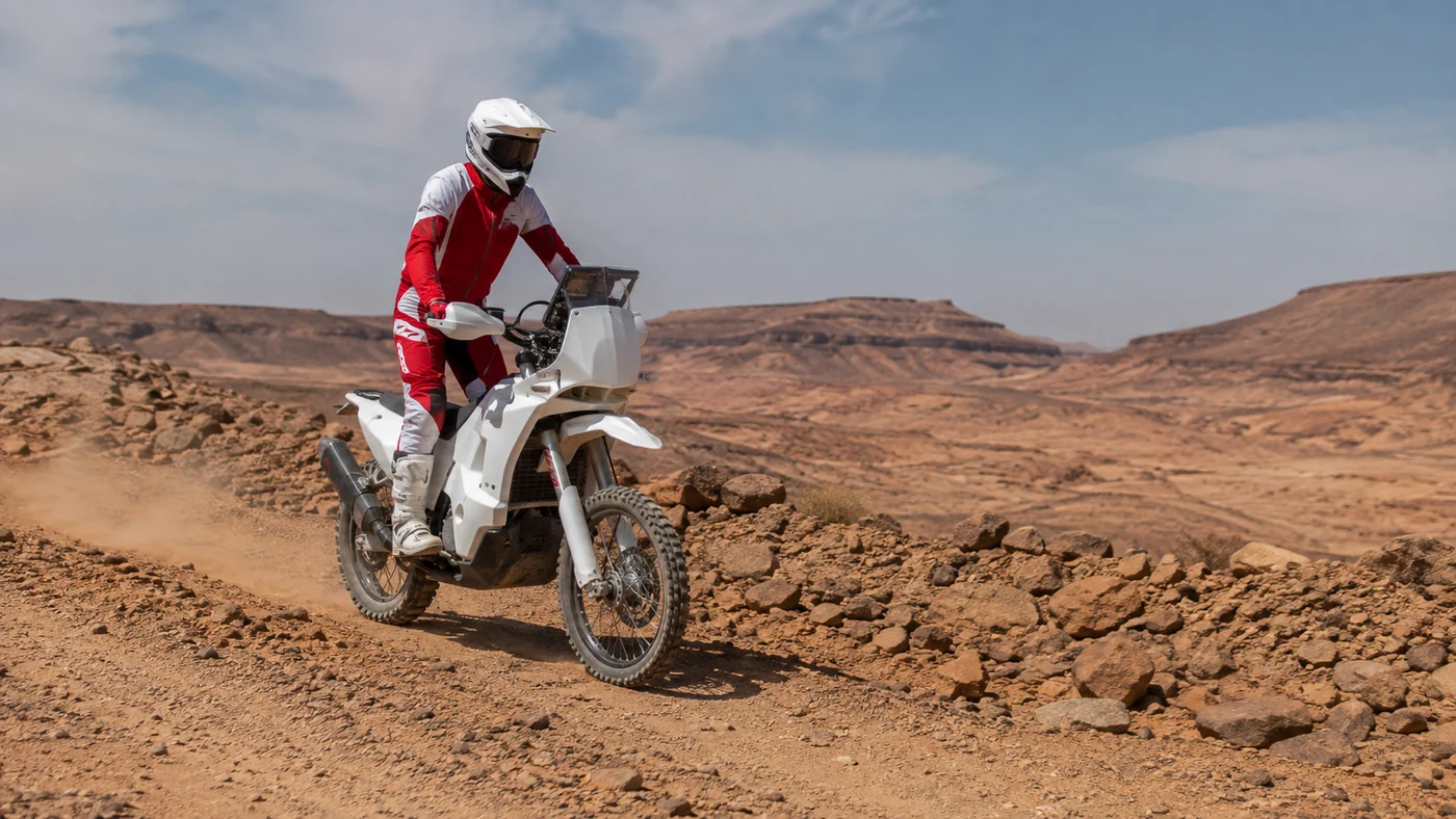 Solo motorcycle rider standing on the foot pegs along a stony desert trail