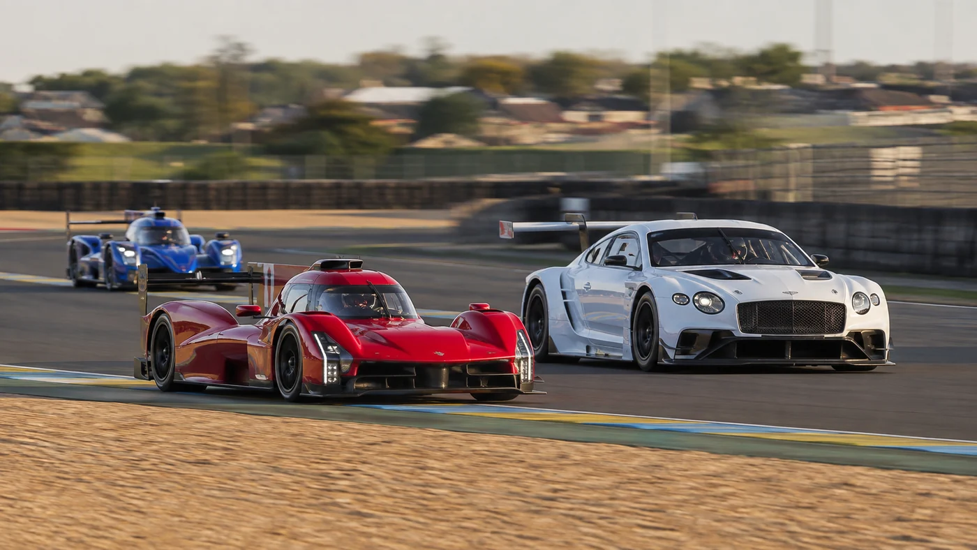 Red and blue endurance prototypes sharing a corner exit with a white GT racing coupe