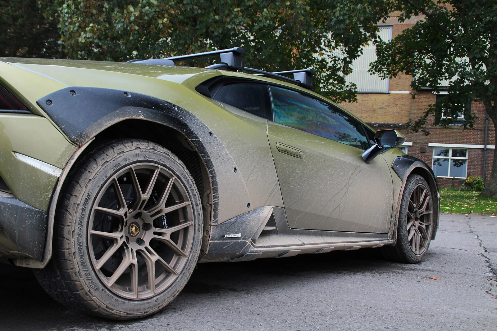 Mud-covered Lamborghini Huracán Sterrato showing raised suspension and all-terrain tyre