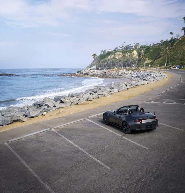 Mazda MX-5 Miata soft top parked beside the coast