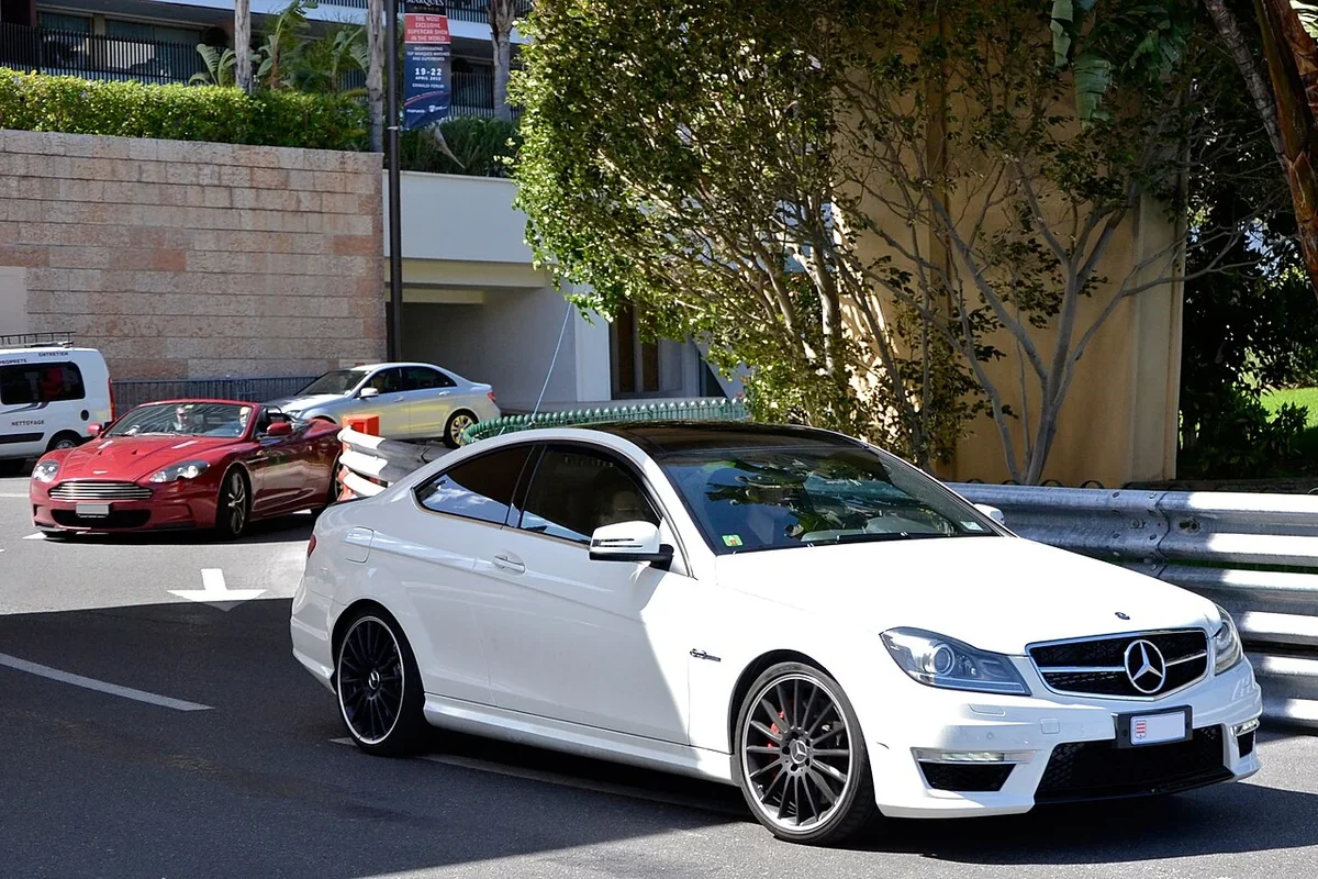 White Mercedes C63 AMG coupe on a tree-lined street