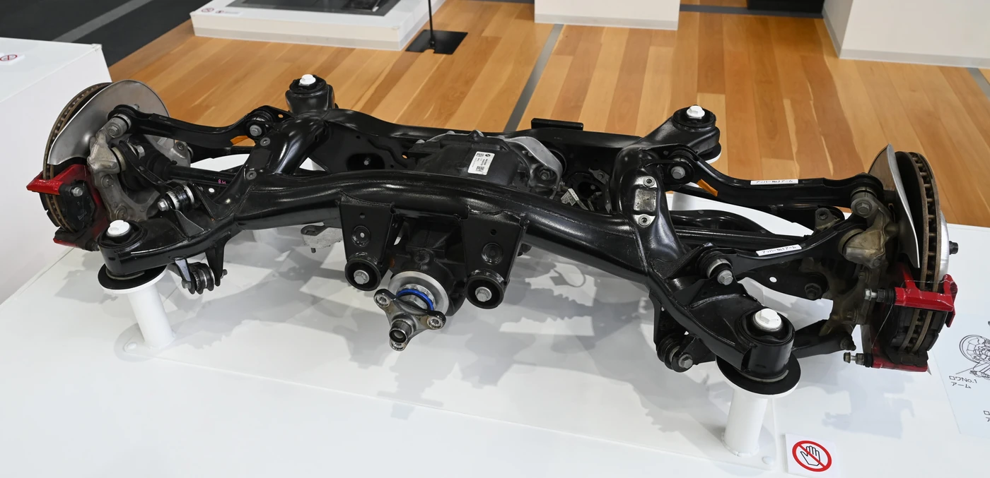 Toyota Supra A90 rear suspension exhibit showing separate wheel links, a black subframe and the central differential