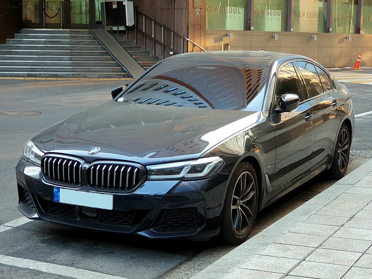 BMW 520i black facelift M Sport opposite front three-quarter view