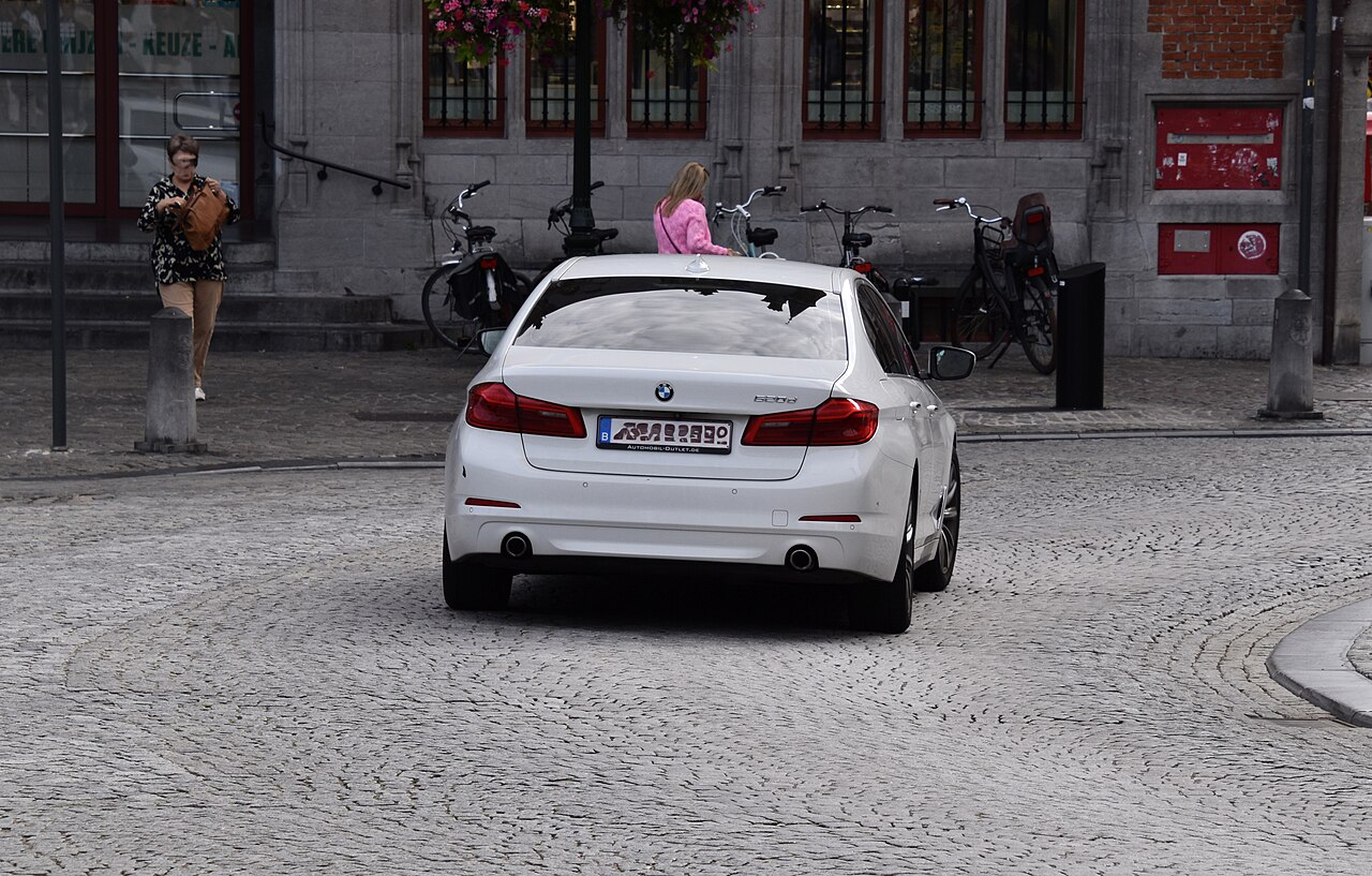 White G30 BMW 520d rear view on a cobbled street