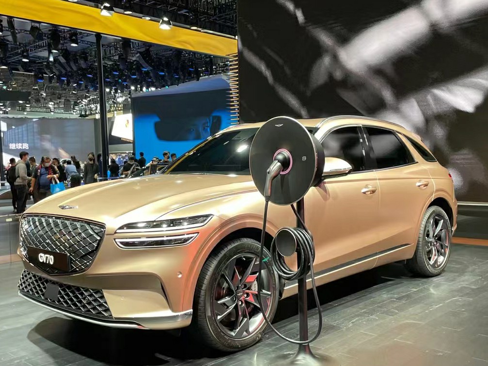 Genesis Electrified GV70 displayed beside a charging stand